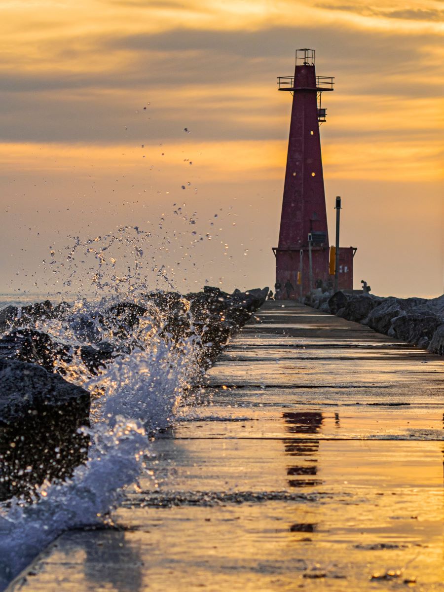 Lighthouse at sunset with splash of water 